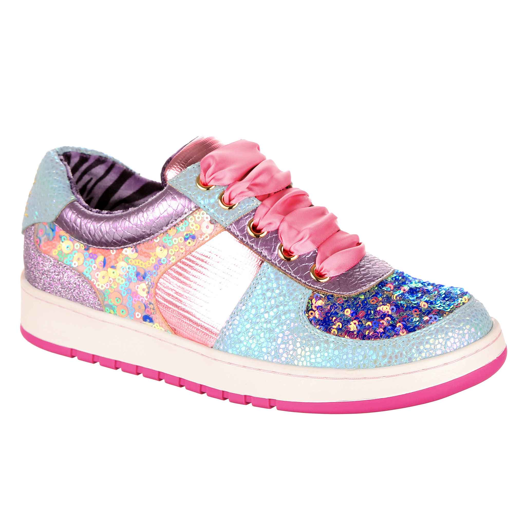 A trainer with white and pink rubber outsole, and an upper in patchwork glittery and sequinned fabrics in pink, purple and blue. It is laced with pink satin ribbon laces.