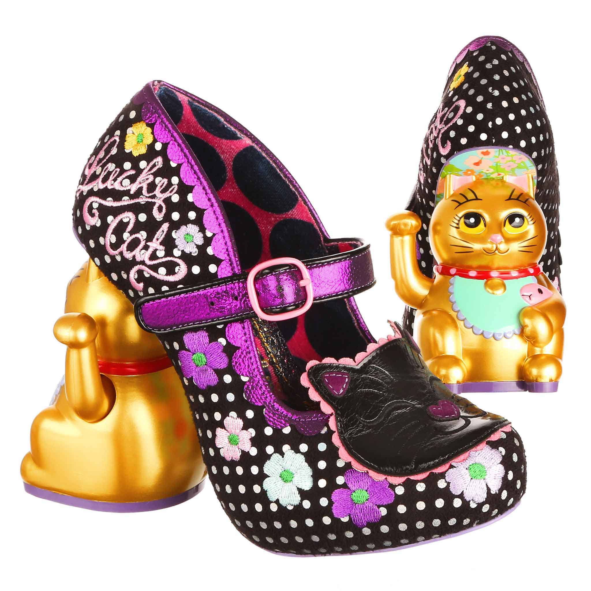 Decorative high-heeled shoe with black polka dot pattern and floral details, paired with a gold cat figurine concept heel on a white background.